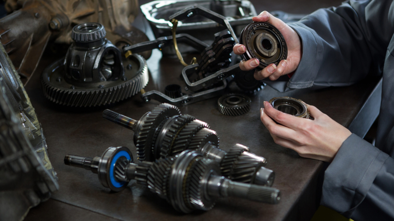 Close-up of female mechanic holding spare parts of car at repair garage