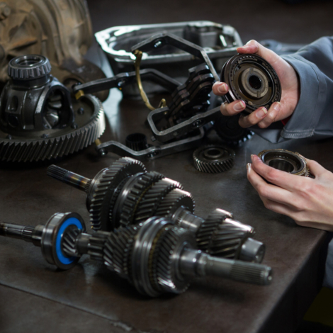 Close-up of female mechanic holding spare parts of car at repair garage